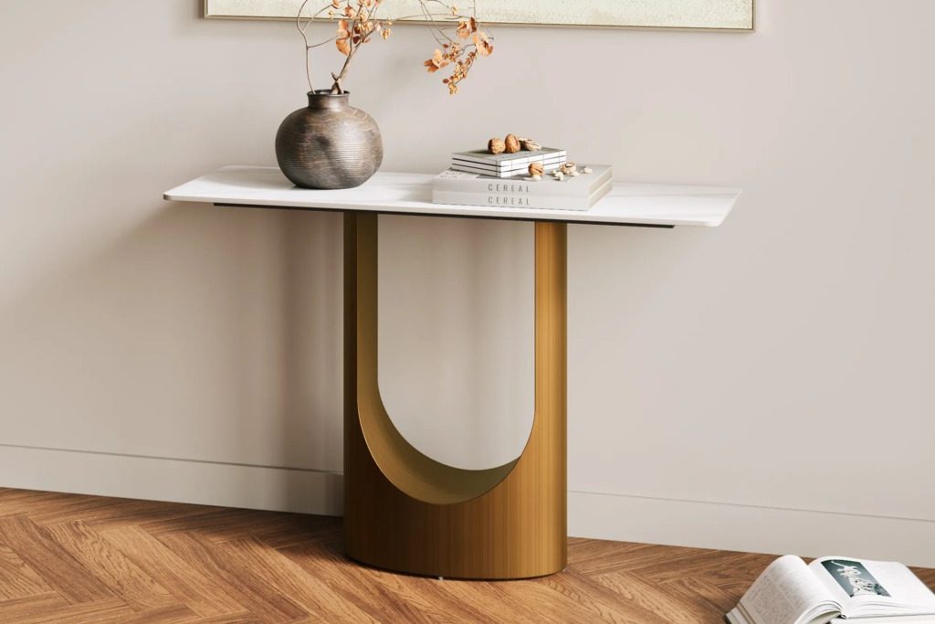 Modern console table with a white top and curved wood base, styled with books and a vase against a neutral wall.