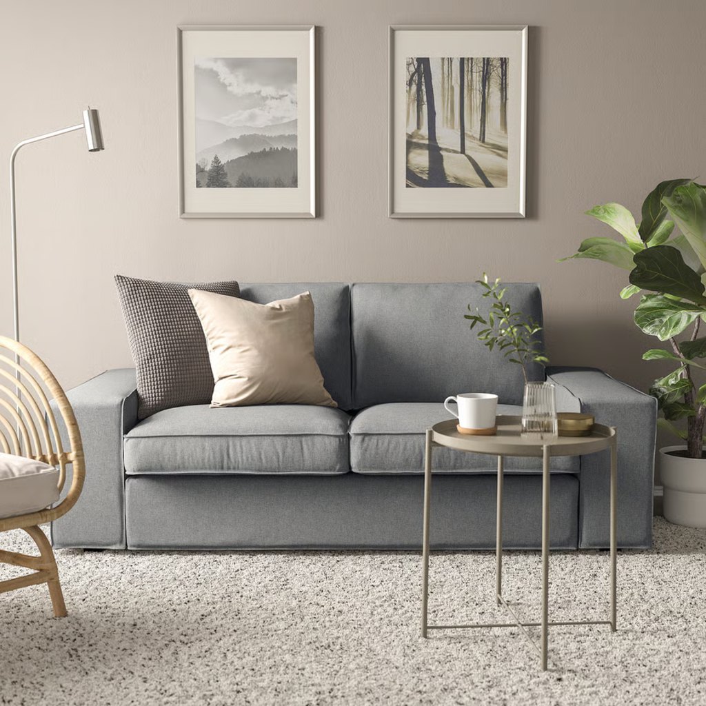 Gray two-seat sofa in a bright modern reading corner with plants and framed wall art