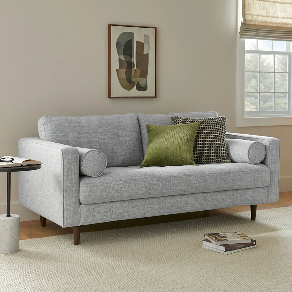 Gray loveseat with bolster pillows in a bright modern teen reading room