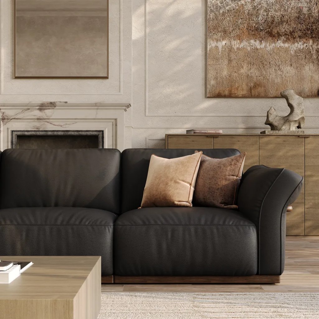Black leather sofa with neutral pillows in a warm living room with wood furniture and abstract wall art.