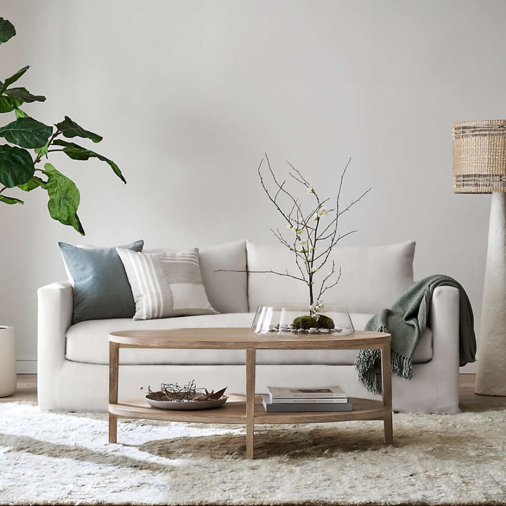 White sleeper sofa in a cozy living room with a wooden coffee table, pillows, and a floor lamp