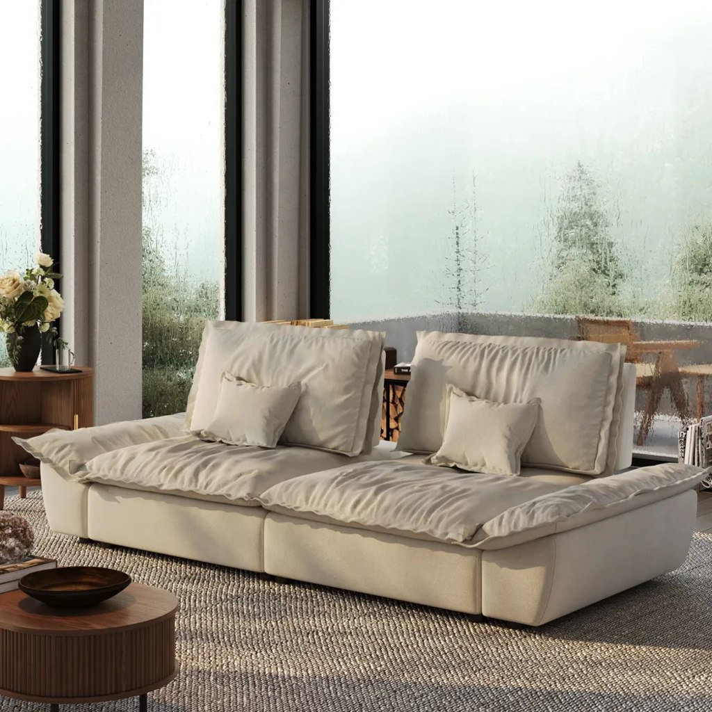 Cream deep-seat sofa with oversized cushions and lumbar pillows beside rain-covered windows.