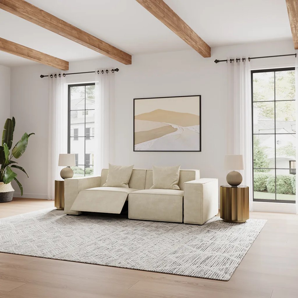 Cream power reclining loveseat with one footrest extended in a bright living room with exposed wood beams.