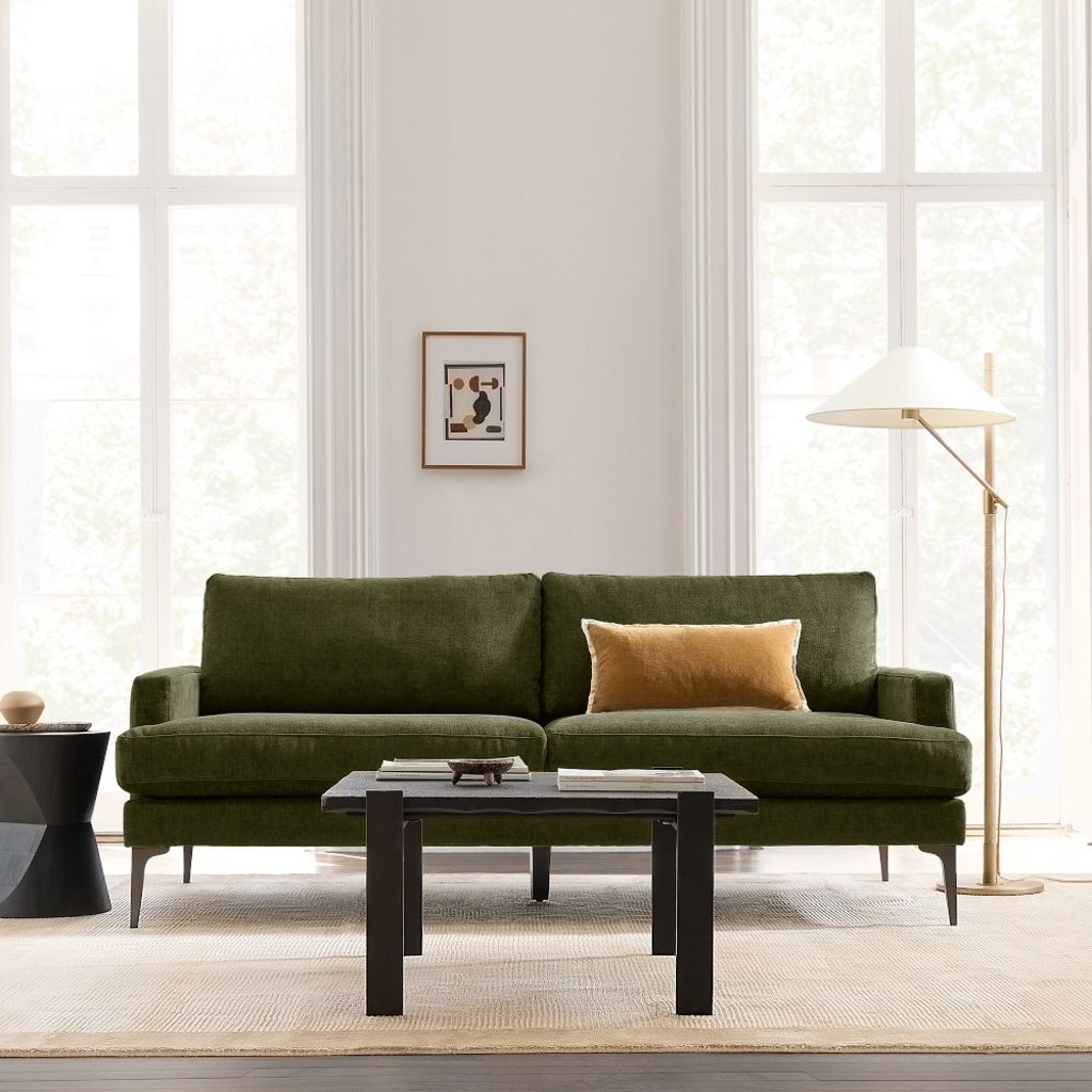 Green upholstered sofa with supportive cushions in a bright modern living room.
