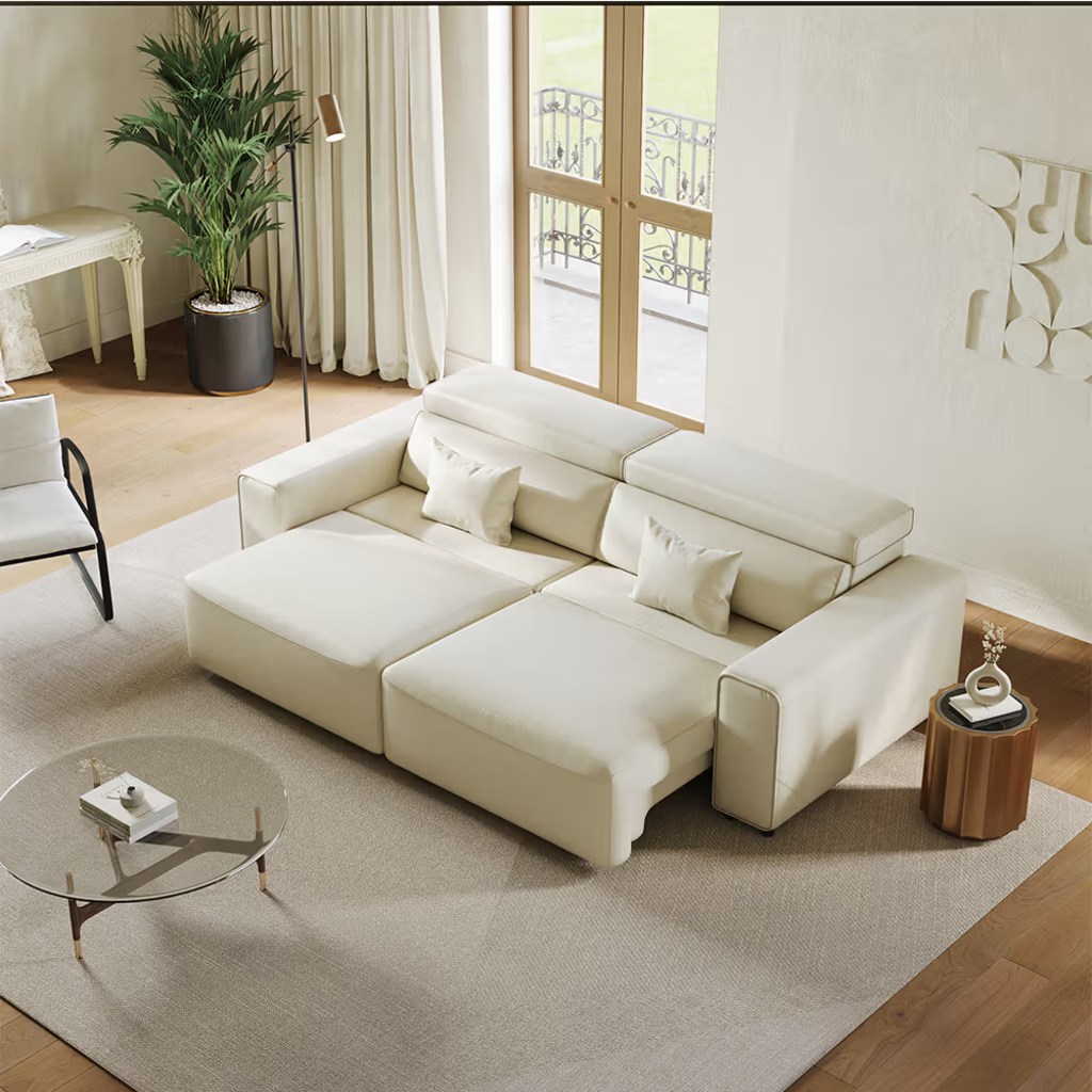 Cream power sofa bed with extended seats, adjustable headrests, and lumbar pillows in a bright modern living room.