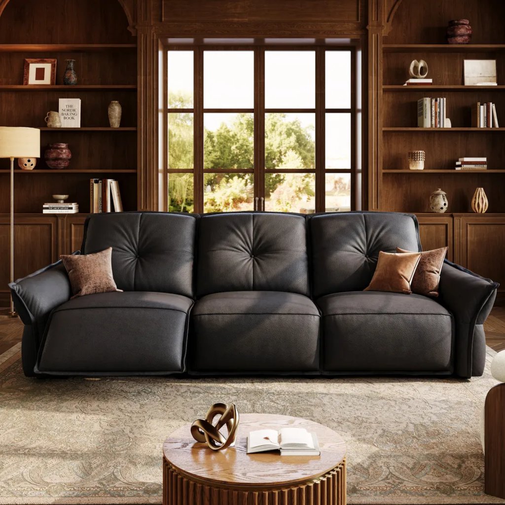 Black leather reclining sofa in a warm living room with built-in wood shelves and a round coffee table.