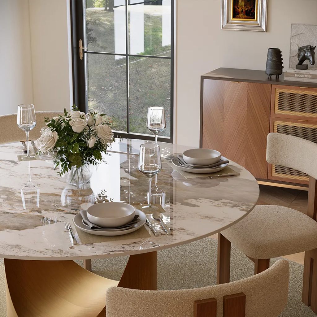 Elegant dining room with a round marble table, neutral place settings, a low white floral centerpiece, upholstered chairs, and a wood sideboard.