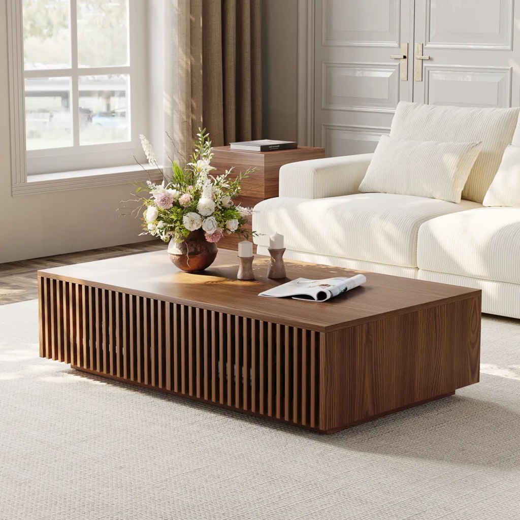 Walnut slatted coffee table with floral decor in a bright living room beside a white sofa.