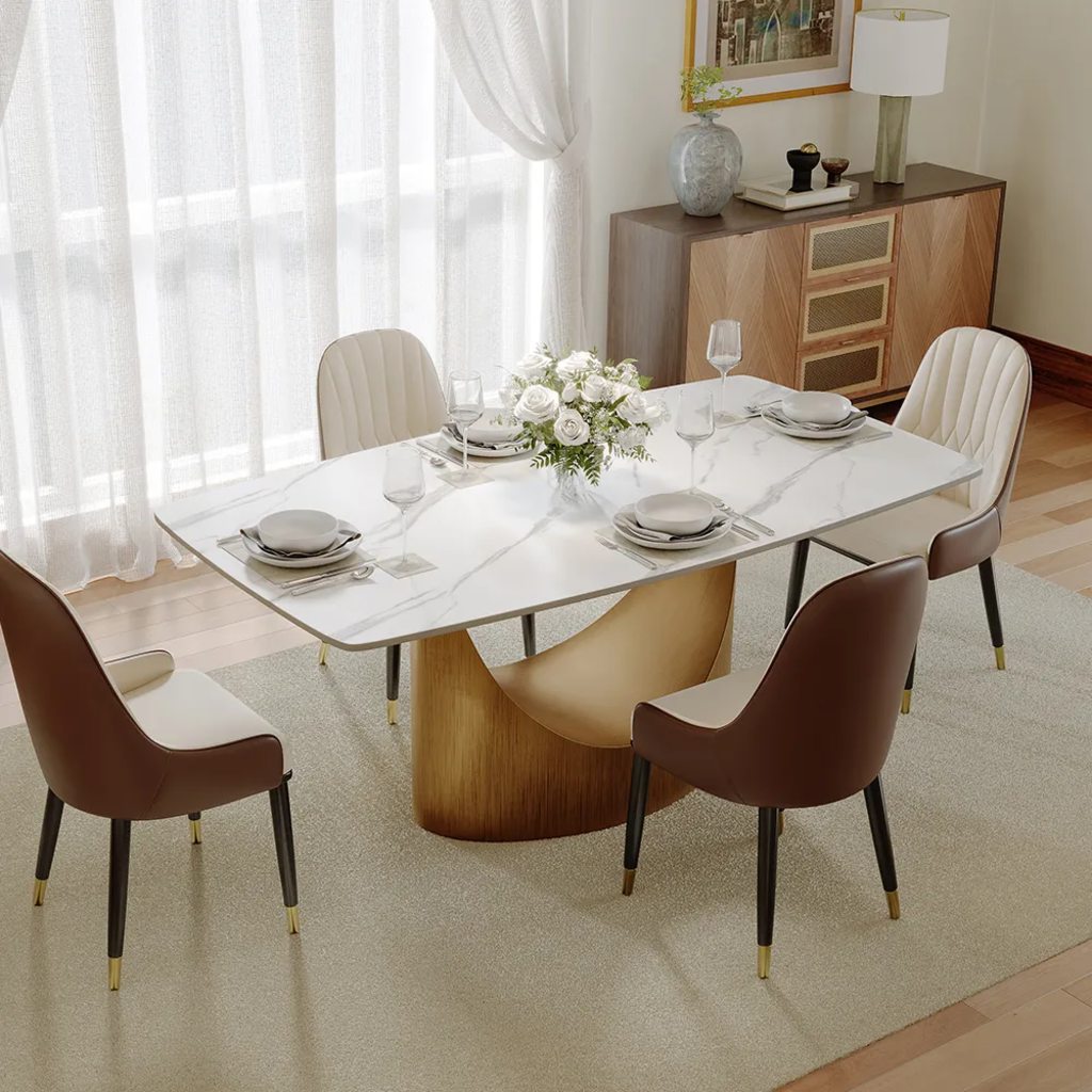 White sintered stone dining table with a curved wood base, paired with brown and cream upholstered chairs in a bright dining room.