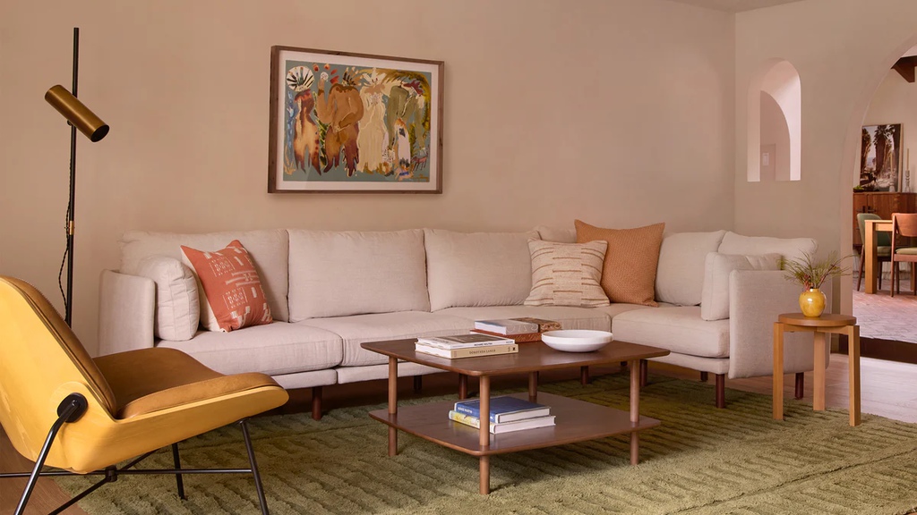 Large cream L-shaped sectional sofa with throw pillows in a warm modern living room.