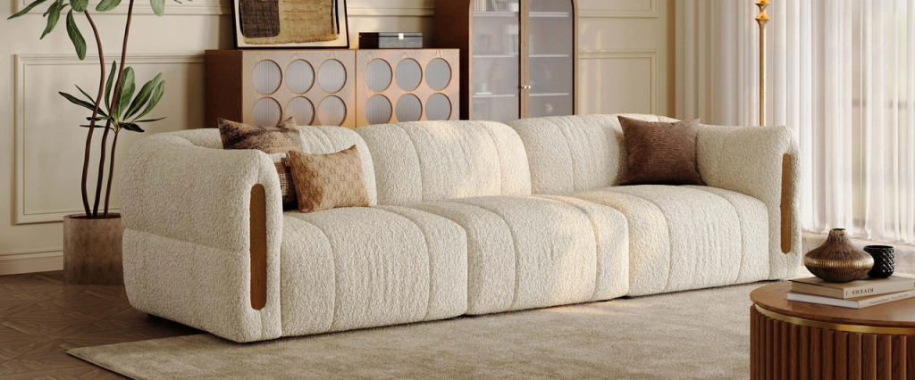 Beige bouclé sofa with solid wood armrest inlays in a warm neutral living room.