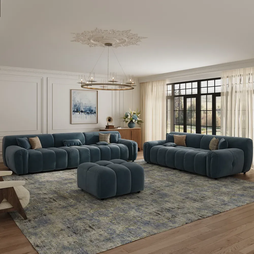 Dark blue velvet sofa set with channel-tufted upholstery and matching ottoman in a bright living room.