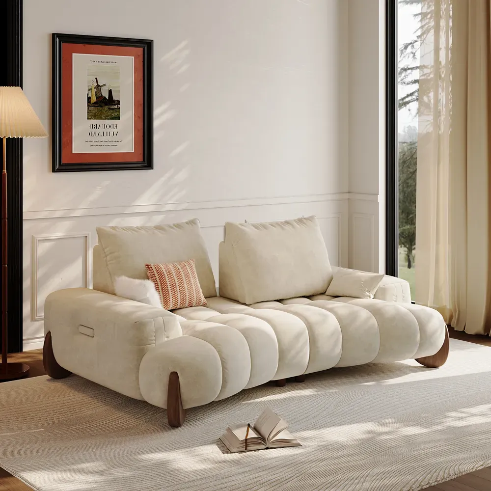 Cream two-seat loveseat with oversized cushions in a bright sitting area beside a tall window.