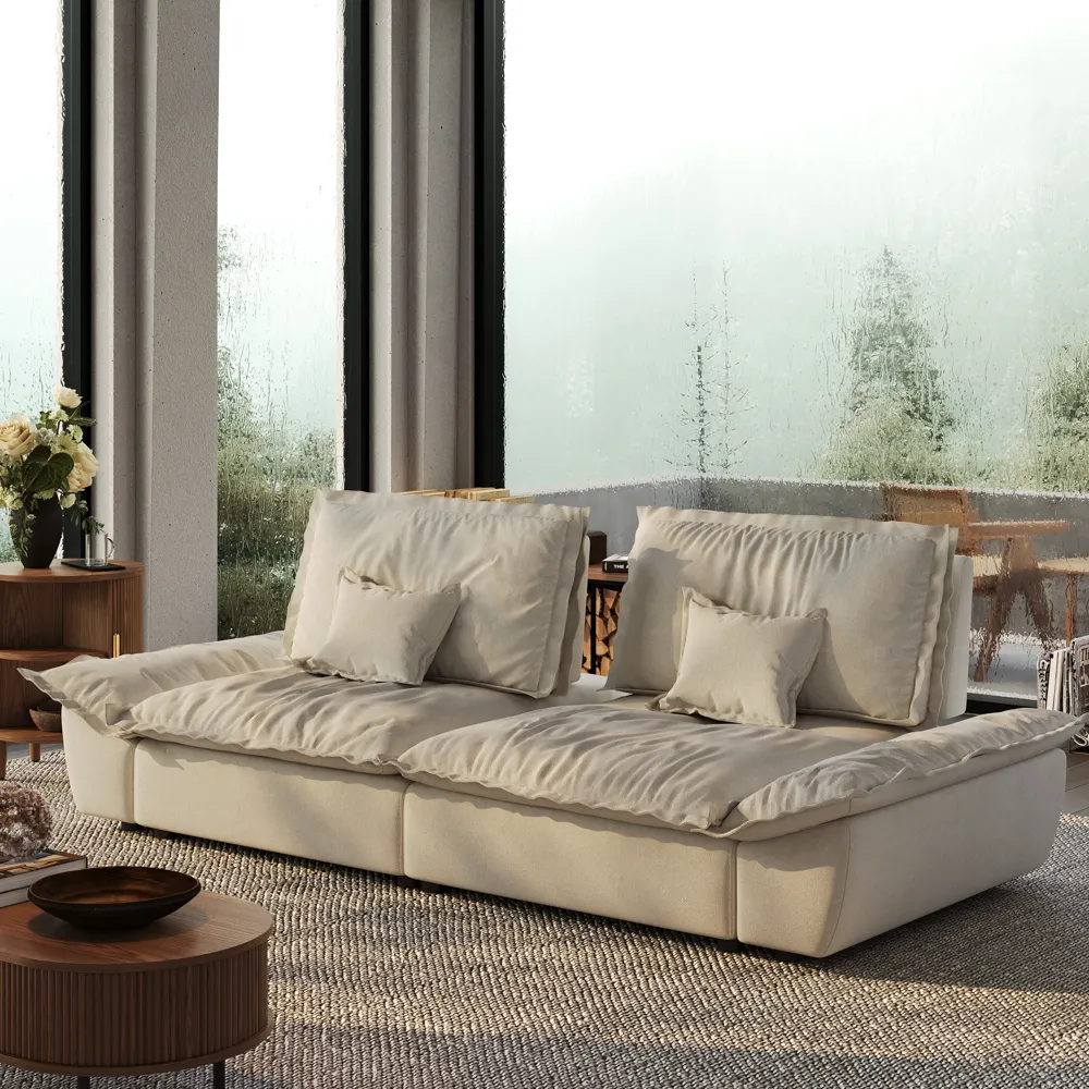 Beige deep-seat sofa in a bright beach home living room with large windows and a round wood coffee table.