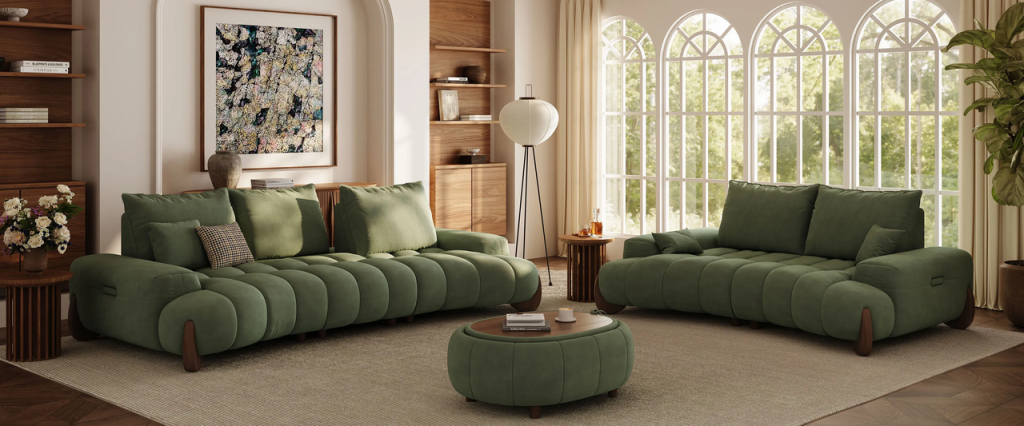 Two green upholstered sofas with a matching round ottoman in a bright living room with large arched windows.