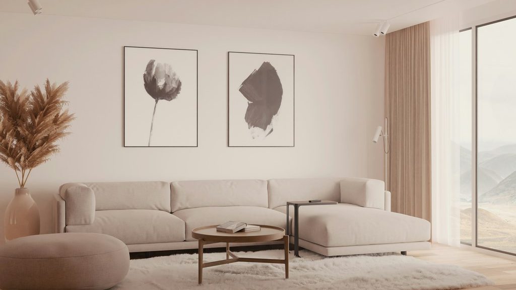 Neutral living room with a cream sectional, two framed abstract prints, a round coffee table, and floor-to-ceiling windows.
