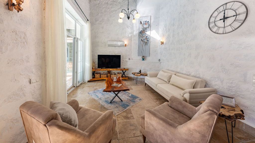 White sofa and two upholstered armchairs arranged around a wooden coffee table in a high-ceiling conversational living room.