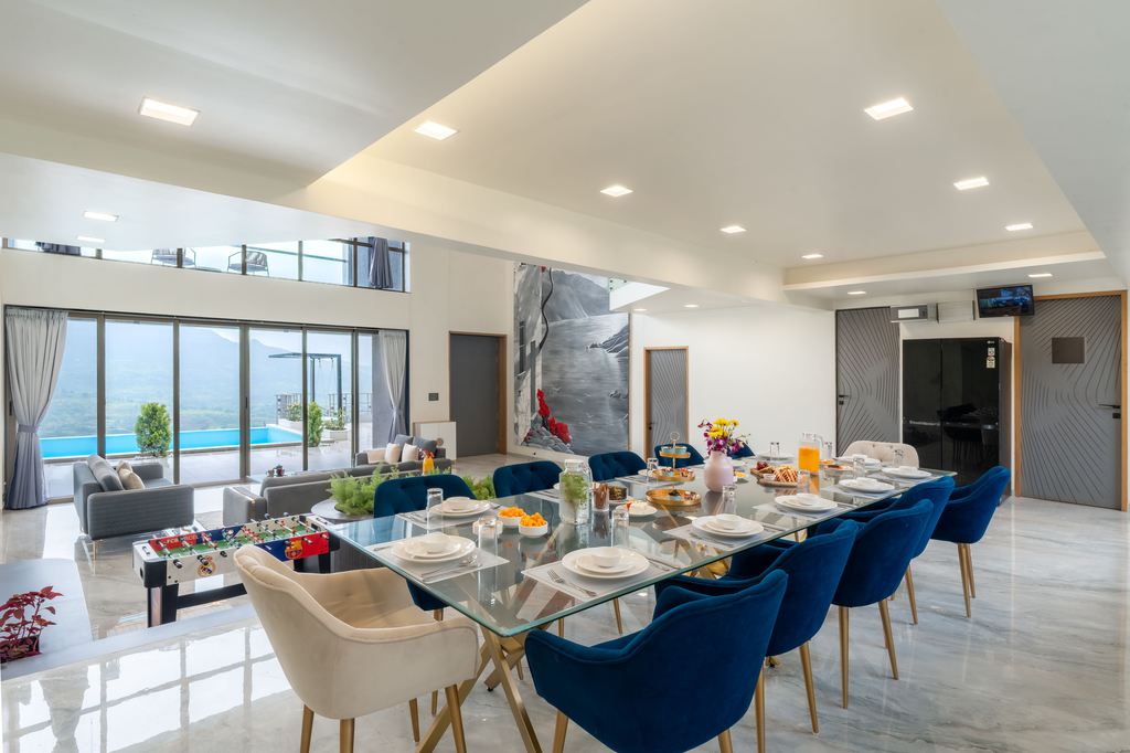 Large glass dining table set for ten in a spacious open-plan living and dining room.