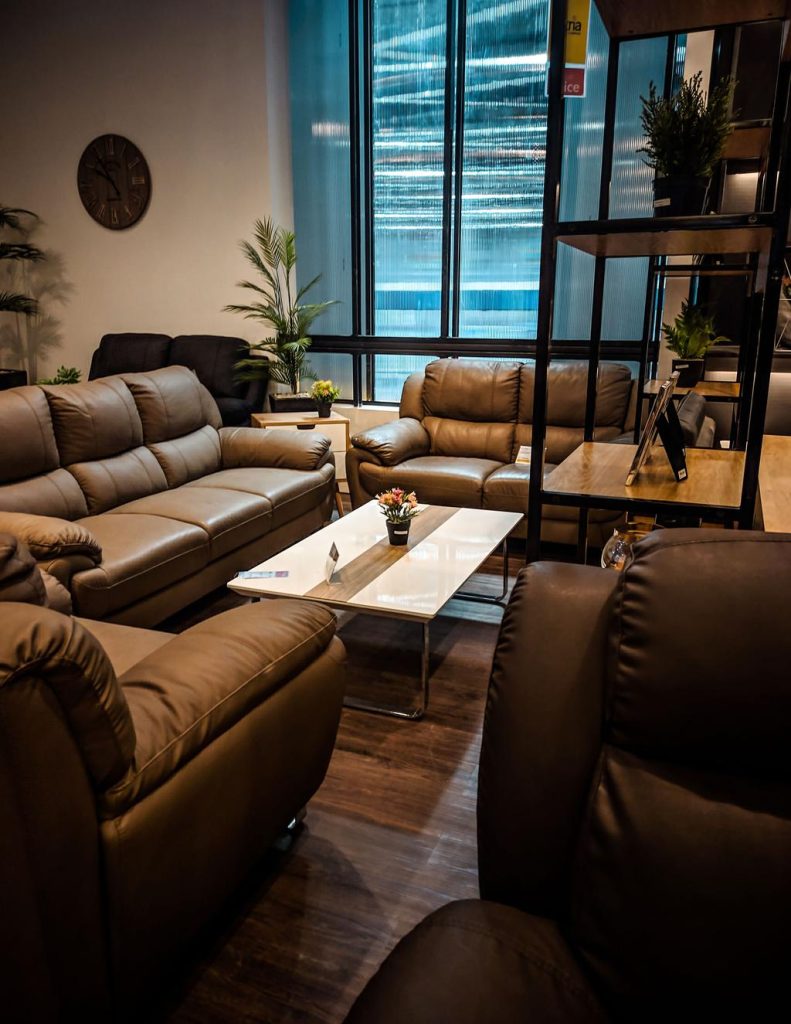 Brown leather sofa set arranged around a rectangular coffee table in a modern furniture showroom