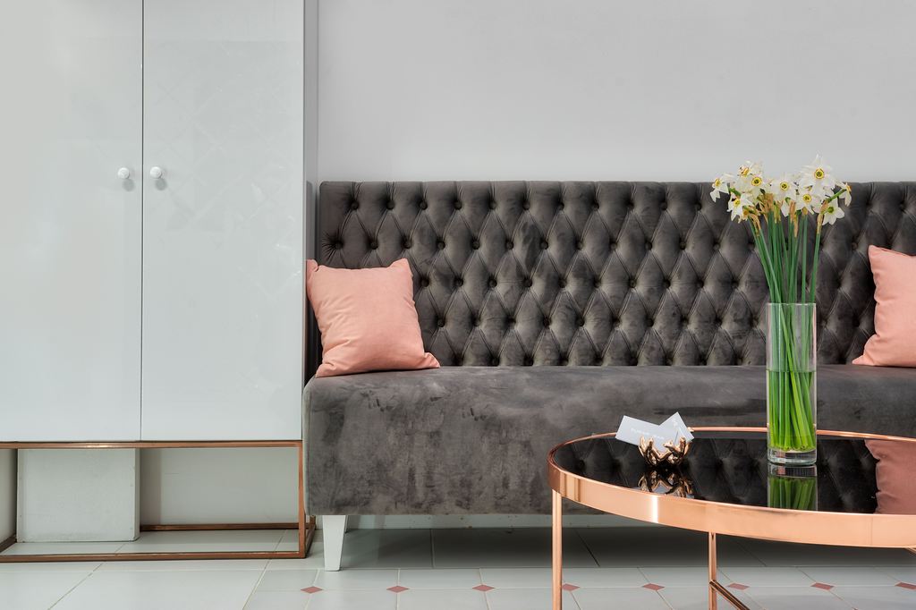 Gray high-back tufted sofa with pink accent pillows in a modern living room.