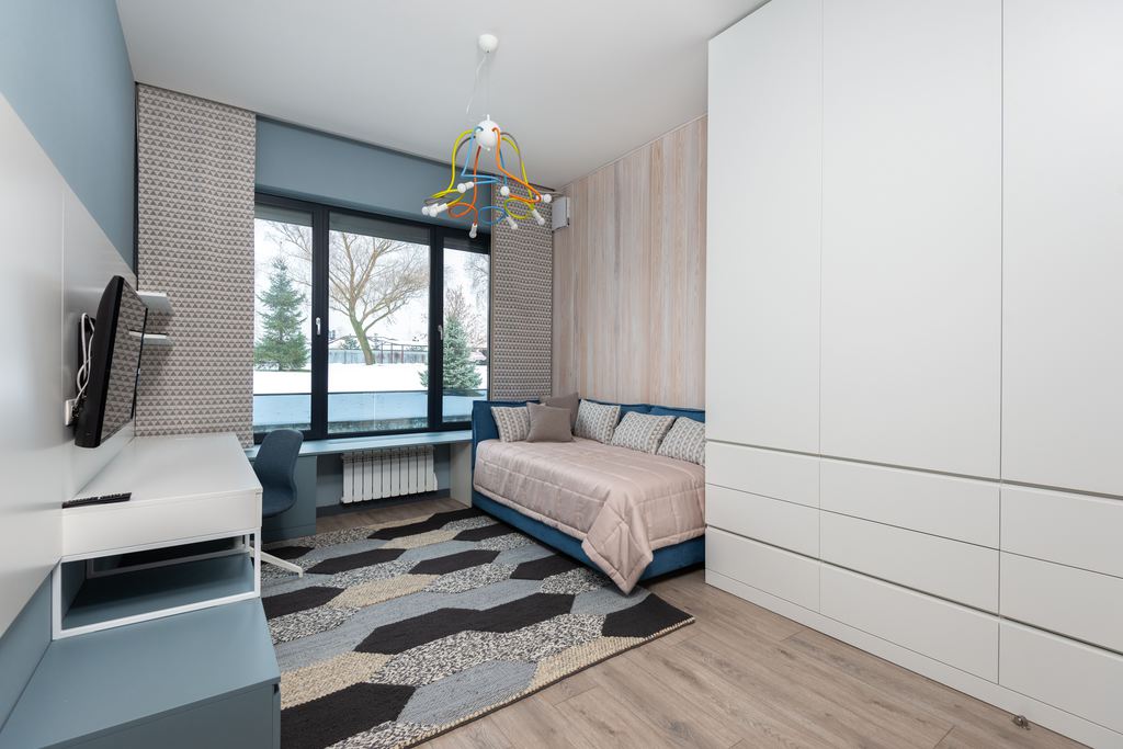 Modern kids’ room with a sofa bed, study desk, TV, and built-in wardrobe