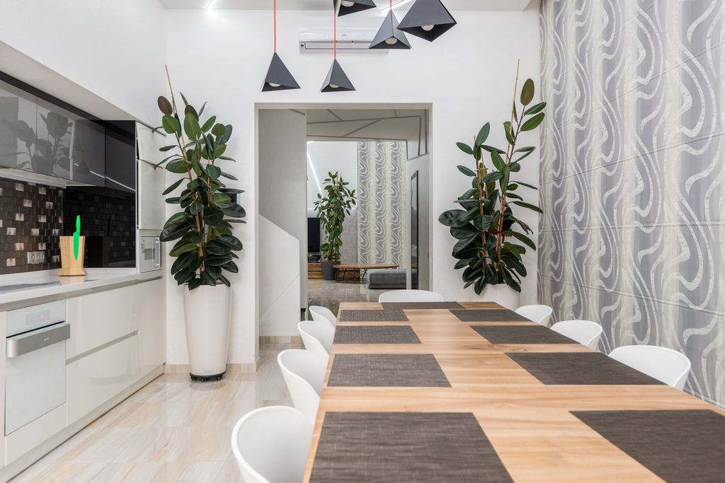 Large rectangular wooden dining table with white chairs in a modern kitchen dining area.