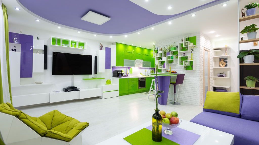 Postmodern open-plan living room and kitchen with purple and lime green furniture, geometric shelving, and curved ceiling details.