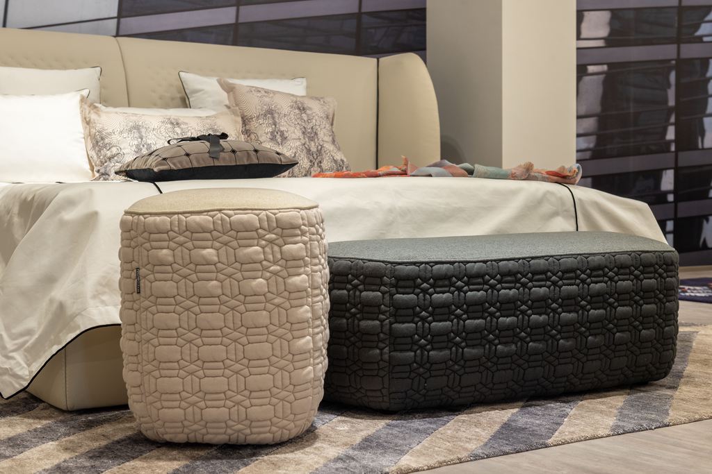 Cream round ottoman and black rectangular ottoman bench at the foot of a modern bed.