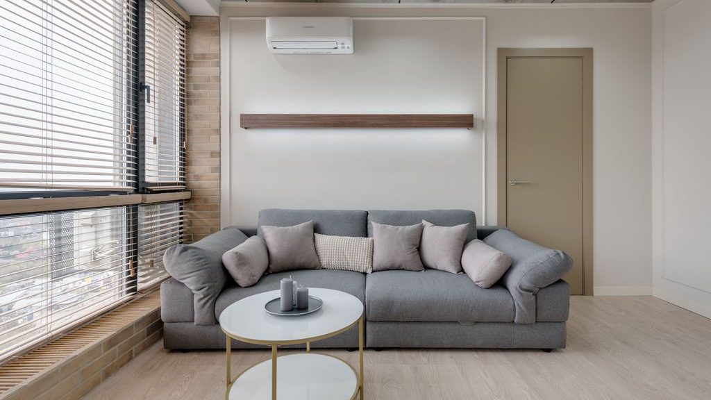 Gray sofa in a compact living room with a round coffee table and large windows.