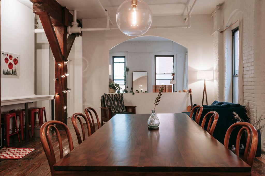 Long dark wood dining table with eight bentwood chairs in an open-plan loft.