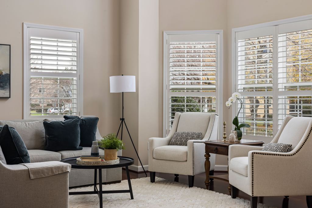 Sofa and two cream armchairs arranged around a round coffee table in a bright conversational living room.
