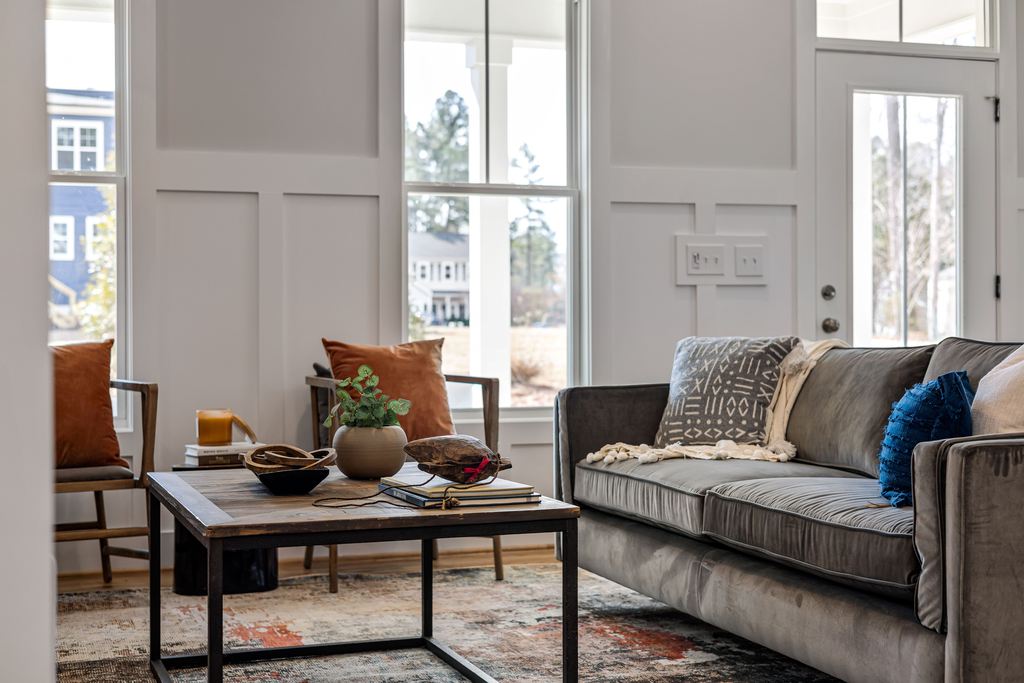 Modern Airbnb living room with a gray sofa, accent chairs, and a wood coffee table in a bright, guest-ready space
