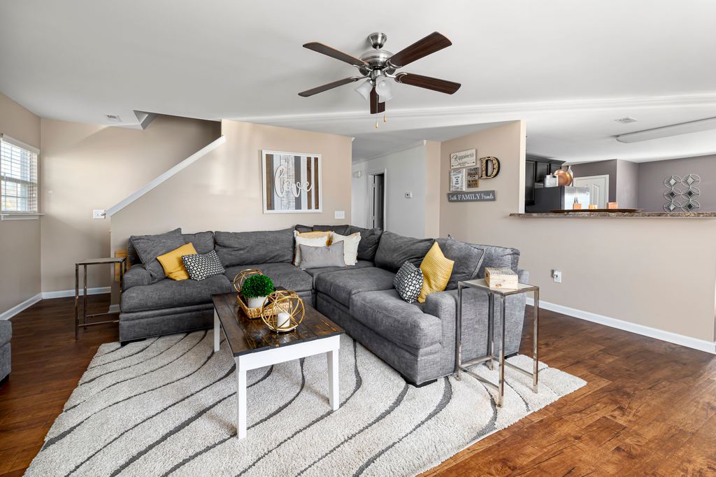 Gray L-shaped sectional sofa with colorful pillows in a spacious open-plan living room.