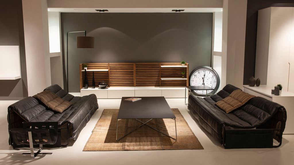 Two black leather sofas facing a square coffee table in a modern living room.
