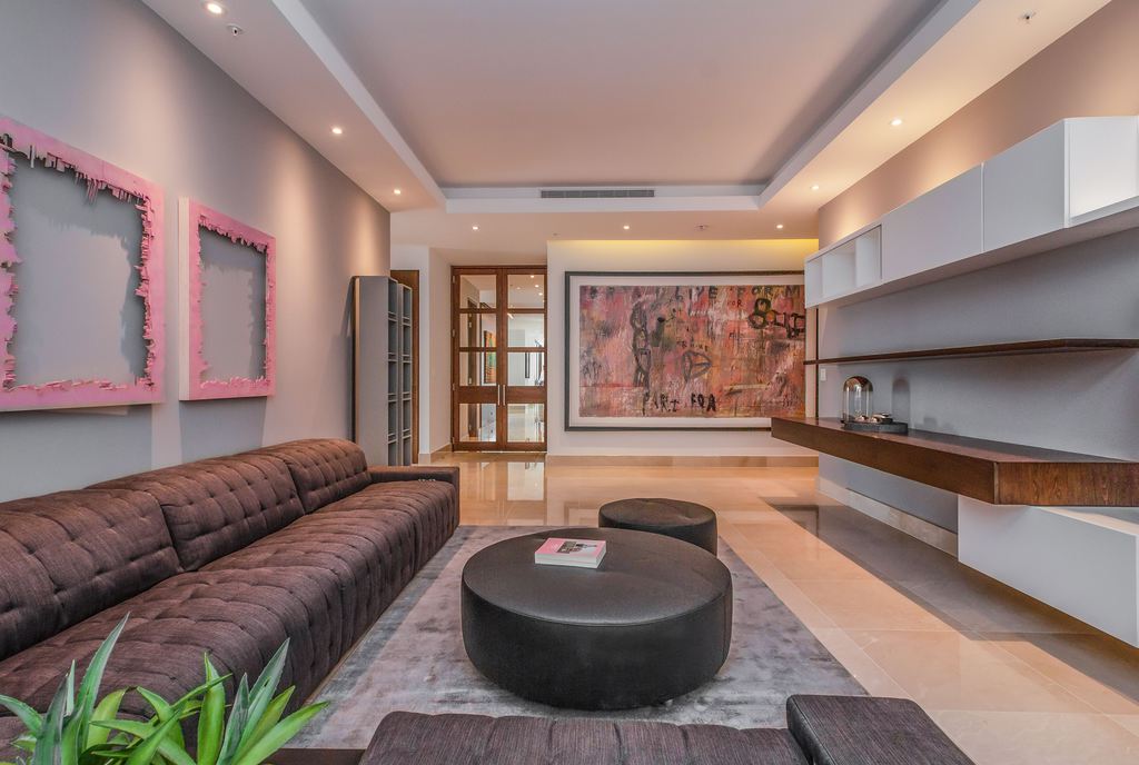 Large round black ottoman used as a coffee table with a book in a modern living room.