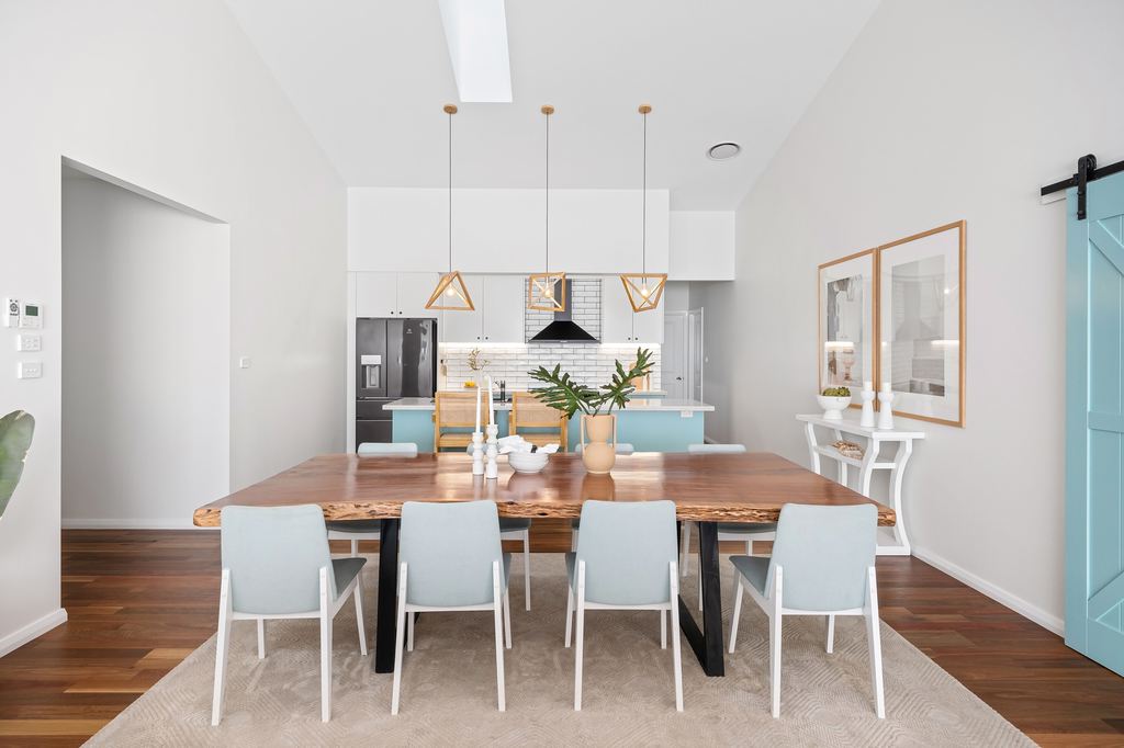 Large live-edge wood dining table with eight chairs in a bright open-plan kitchen.