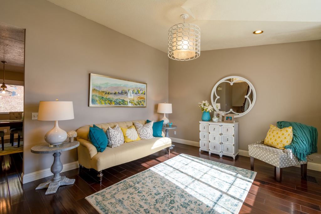 Living room without a coffee table, featuring a beige sofa, accent chair, side tables, patterned rug, and open central floor space.