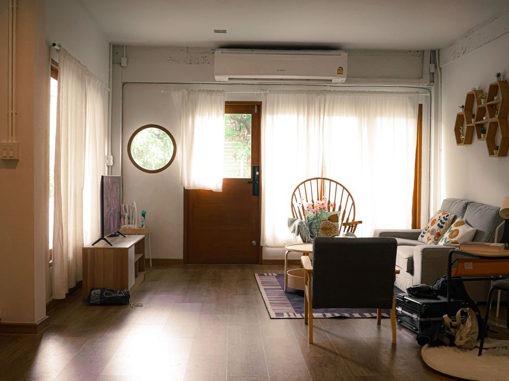 Small living room with a gray sofa, contrasting armchairs, a wood media console, and mixed modern and natural furniture styles.