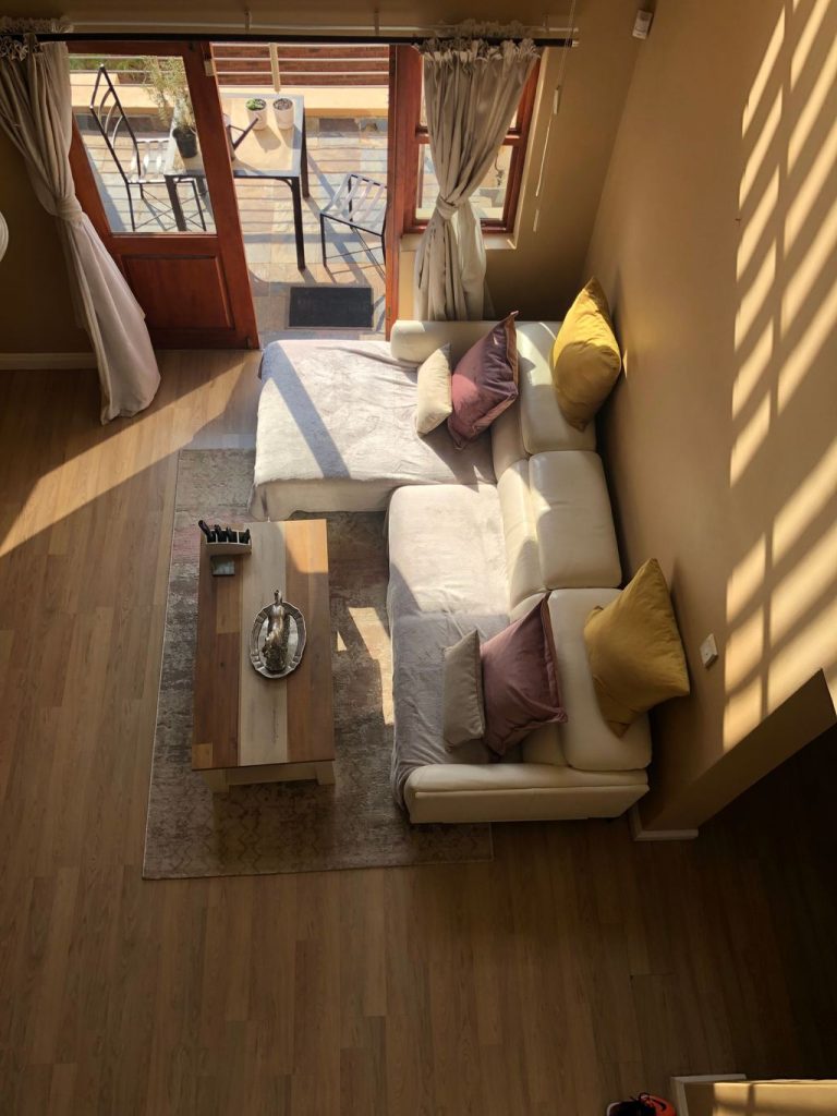 Rectangular wood coffee table centered in front of a cream L-shaped sectional sofa on an area rug