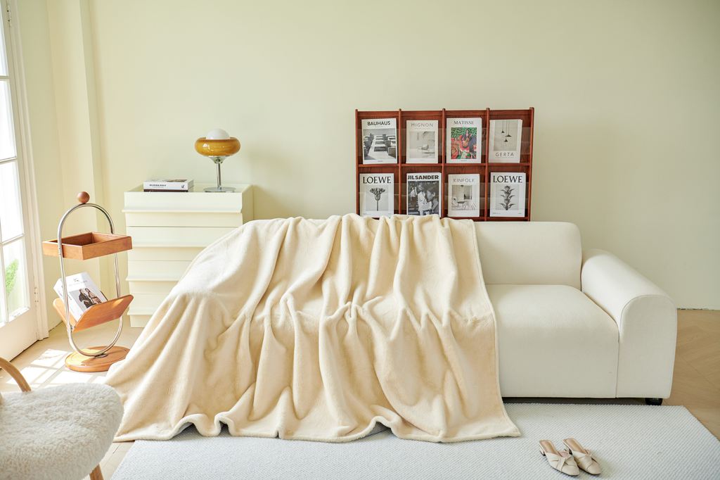 White sofa with a cream blanket in a bright living room with soft neutral decor.