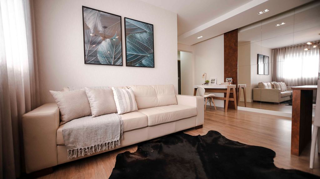 Light beige leather sofa in a modern living room with wood flooring, mirrored walls, and a black rug.