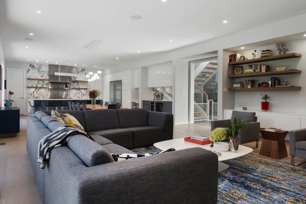 Dark gray sectional paired with contemporary armchairs, a white coffee table, and a sculptural wood side table in a mixed-style open-plan living room.