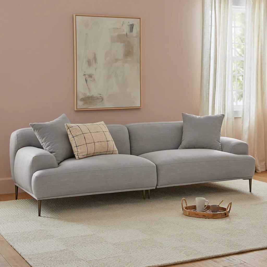 Light gray low back sofa with slim metal legs and accent pillows in a soft neutral living room.