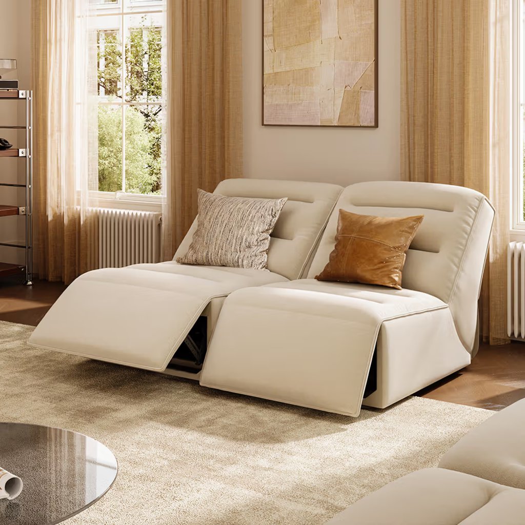 Cream two-seat reclining sofa with both footrests extended in a bright, neutral living room.