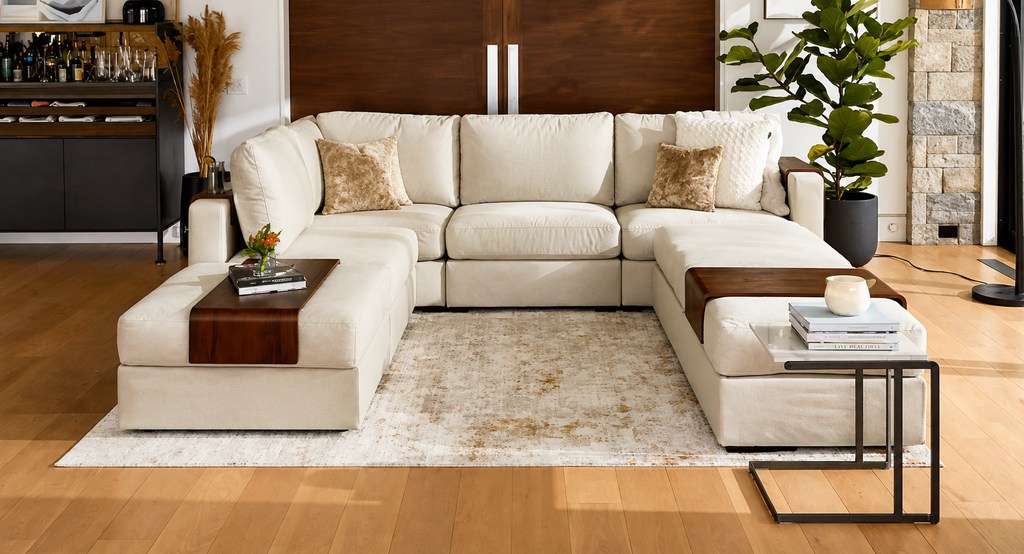 Cream U-shaped sectional sofa with dual chaises and wood tray tables in a bright shared apartment living room.