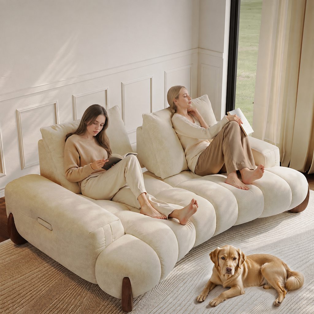 Two women reading on a deep cream sofa with plush cushions and a dog resting nearby.