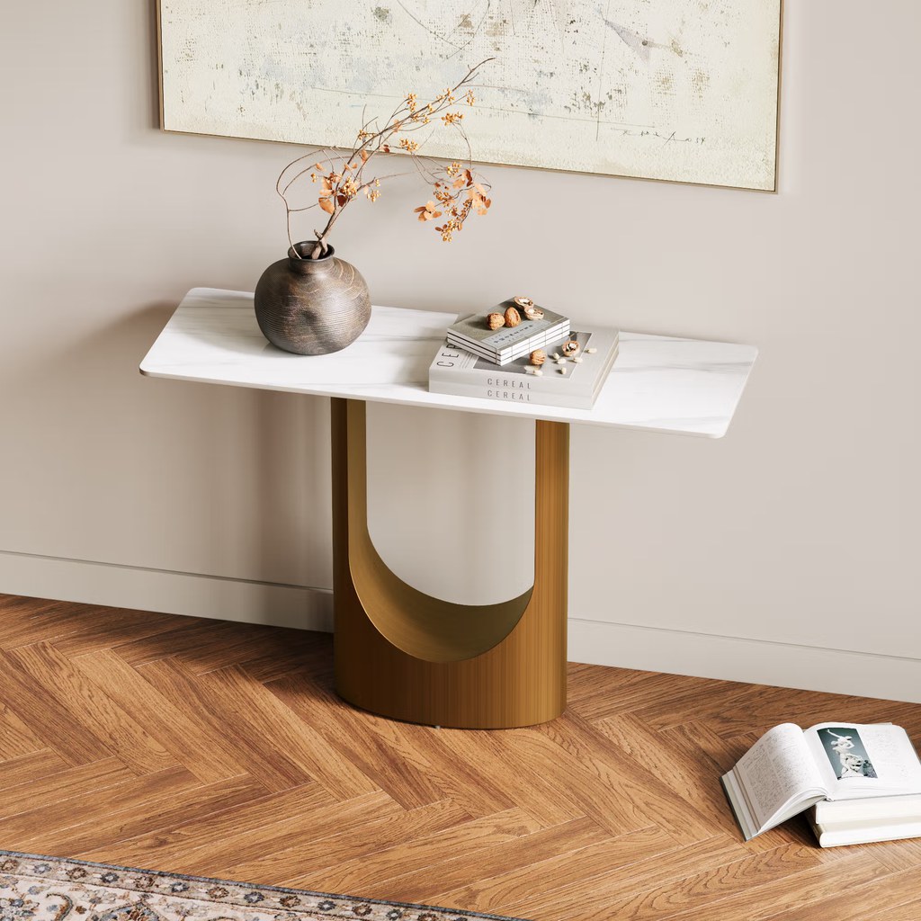 Modern marble-top console table with a curved base, decorative vase, books, and wall art in a minimalist interior.