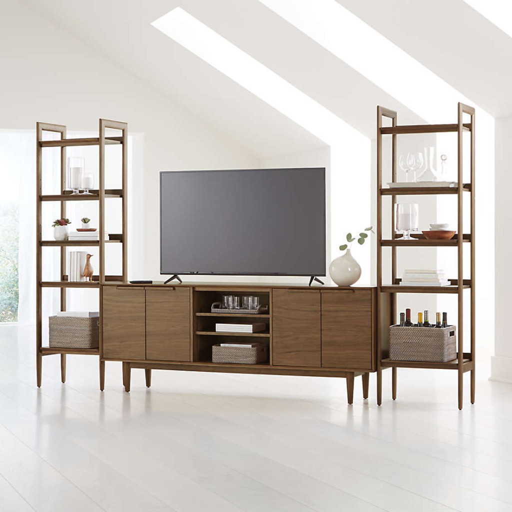 Walnut media console with open center shelves and matching tall bookcases supporting a flat-screen TV in a bright living room.