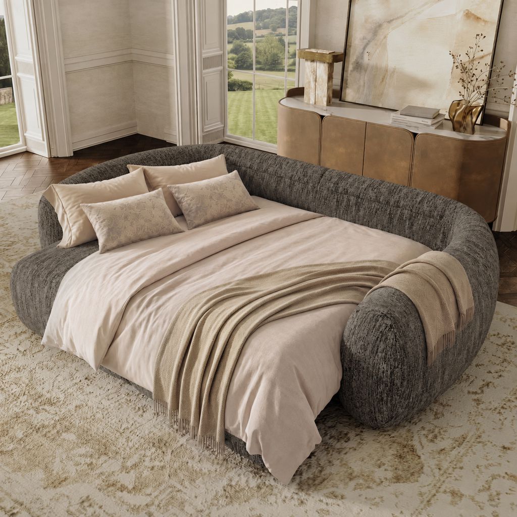 Gray curved sofa bed fully extended with beige bedding in an elegant neutral living room.
