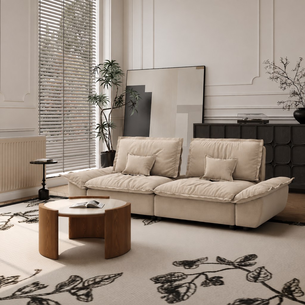 Beige sailboat-style sofa in a bright modern living room with a round wood coffee table and botanical rug.